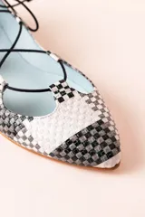 Bailarinas con base de napa trenzada en tonos blanco, negro y gris con diseño de damero. Cierre con cordones negros y detalle de borlas en la parte trasera. Diseñadas y producidas de forma artesanal 100% en España con materiales de alta calidad y suela de cuero.