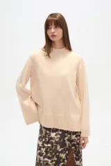 Sweater de viscosa color beige, con cuello polera, corte holgado y pespuntes decorativos en el frente.