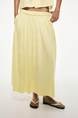 Falda midi color amarillo pastel, de tiro alto con cintura elástica, bolsillos laterales y forro interior a contraste.