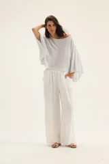 Pantalón de lino color beige, de corte palazzo y terminación con flecos.