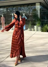 Vestido midi color marrón ocre con estampado de pata de gallo, corte cruzado, mangas largas abullonadas y lazo en la cintura.