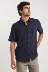 Camisa sport de manga corta, color azul marino, con botones de coco y un bolsillo en el pecho. Confeccionada en lino y algodón.