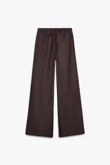 Pantalón palazzo color ladrillo confeccionado en lino 100%, de tiro medio con cintura ajustable con cordones, bolsillos laterales ocultos en costura y pierna ancha.