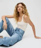 Pantalón de jean de algodón, modelo recto, con cintura mediana y trabillas. Presenta bolsillos delanteros y traseros, y un estampado localizado de flores de hibiscos.