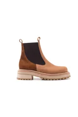 Bota Chelsea color marrón con paneles laterales elásticos negros, suela track color beige y tiradores en la parte superior.