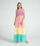 Vestido largo de poliéster con bloques de color: lila en el corpiño elastizado, rosa en la parte superior de la falda, amarillo en la parte media y turquesa en el ruedo.