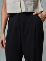 Pantalón negro de vestir, de corte recto y tiro alto, con pinzas en la cintura y bolsillos laterales.