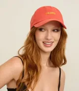 Gorra de sarga de algodón color coral o salmón con visera curva y bordado frontal en hilo amarillo con la palabra "Caliente".