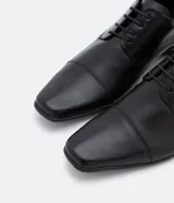 Zapato de vestir negro para hombre, confeccionado en cuero, con cordones y puntera reforzada.