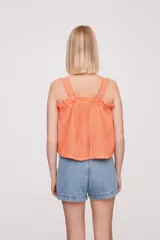 Musculosa color salmón con breteles finos y detalle de puntilla en el escote.