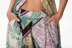 Pantalón sastrero de corte oversize con estampado paisley en tonos verde, lila, marrón y beige. Pretina ancha en la parte delantera y elástico en la parte trasera.