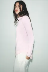 Jersey de punto color borgoña, con cuello redondo, manga larga y bajo con aberturas laterales.
