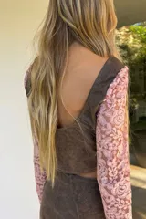 Top negro de cuero con mangas largas de encaje, escote en V y cierre frontal con botones metálicos.