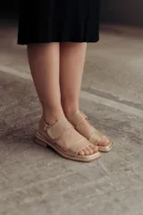 Sandalias bajas doradas de cuero, con punta cuadrada, tiras anchas y cierre con hebilla ajustable.