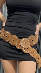 Cinturón marrón de gamuza con discos unidos entre sí y tachas plateadas.