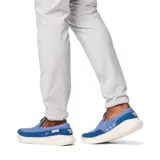 Zapato tipo slip-on para hombre de estilo náutico, marca Columbia modelo Boatside PFG. Presenta un diseño en color azul confeccionado en lona y gamuza, con una suela blanca moteada que incorpora tecnología Omni-GRIP™ LT para tracción y ligereza.