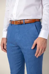 Pantalón de vestir azul marino, de corte recto, confeccionado en lino. Se ajusta a la cintura con cinturón de cuero marrón.