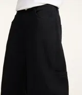Pantalón negro de sarga, corte skater, con bolsillos grandes y recortes deslocados.