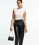 Pantalón zanahoria color marrón claro confeccionado en material sintético con cintura elástica, cordón ajustable con punteras metalizadas, bolsillos laterales y traseros.
