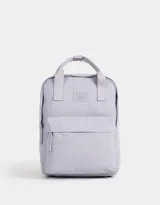 Mochila de tela deportiva color lila con correas regulables, manijas superiores con broche, acceso mediante cierre superior con tirador de cuerina, bolsillo frontal con cierre y tirador de cuerina, y etiqueta de goma.