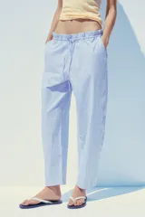 Pantalón tipo barrel con rayas verticales celestes y blancas, tiro medio y cintura elástica ajustable con lazo. Tiene bolsillos laterales y falsos bolsillos de vivo en la espalda.