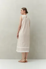 Vestido largo color beige, sin mangas, confeccionado en algodón con calados verticales y bordado tipo ojo de perdiz.