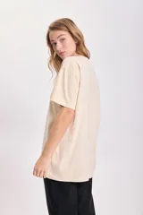 Remera color beige de corte holgado con estampado de una copa de martini en color rojo.