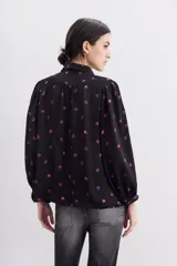 Camisa fluida negra con estampado de corazones color lila, mangas largas, cuello camisero y puños con botón.