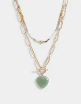 Collar corto doble con cadena dorada de eslabones rectangulares y cadena de mostacillas de colores con dije de corazón dorado y dije de piedra verde en forma de corazón.