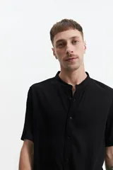 Camisa blanca de manga corta con cuello mao y doblez en las mangas.