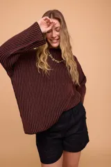 Sweater tejido en algodón color marrón con rayas verticales negras, de corte holgado, mangas anchas y cuello bote. Tejido a contra tono para generar efecto vanizado.