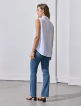 Camisa blanca sin mangas, de lino, con cuello clásico, escote en V, cierre frontal con botones y bolsillo en el pecho.