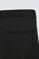 Pantalón negro de corte recto y calce relajado, confeccionado en tejido de algodón con elasticidad. Presenta cintura ajustable con cordón, bolsillos frontales y bolsillos traseros de doble vivo.