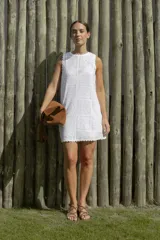 Vestido corto blanco con estampado de flores y diseño geométrico, sin mangas y con terminaciones onduladas en cuello y ruedo.