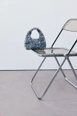 Cartera de mano plateada cubierta de lentejuelas, con asa corta y forro interior.