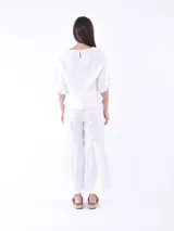 Pantalón blanco de corte cropped y ruedo acampanado con volantes.