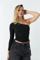 Top asimétrico blanco de una sola manga con jaretas ajustables en ambos lados del torso para regular el largo.