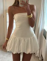 Vestido corto strapless negro con falda globo blanca.