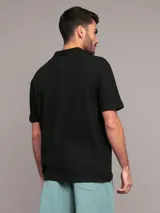 Chomba negra de algodón con textura de crepé, corte regular, manga corta y cuello abierto. Logo de Calvin Klein bordado en el pecho.