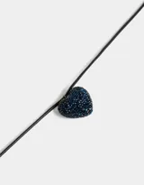 Gargantilla con dije de corazón cubierto de strass azules, colgando de un cordón negro.