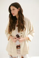 Sobrecamisa beige de corte recto, cuello mao y mangas 3/4. Presenta cierre frontal con botones de madera y bolsillos laterales.
