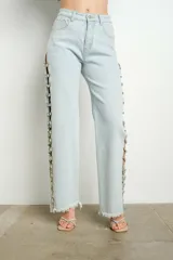 Pantalón de jean celeste con lavado claro, tiro alto, corte recto y apliques de gemas en aberturas laterales.