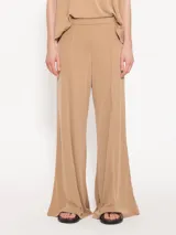 Pantalón palazzo color beige confeccionado en tela de punto con cintura elastizada.