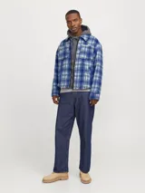 Sobrecamisa corta de manga larga con cuello sport y fit cómodo, confeccionada en tejido plano con efecto lana a cuadros azules y grises. Cuenta con cierre frontal de cremallera, puños con botones, solapa cortaviento, bolsillos en pecho y delanteros.