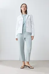 Campera de jean blanca con cuello clásico, bolsillos con solapa abotonados en el pecho y cierre frontal con botones metálicos. Corte recto.
