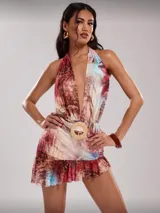 Vestido corto con estampado abstracto en tonos marrones, rojos y celestes. Escote halter con espalda descubierta y falda con volados. Cinturón con hebilla circular de rafia.
