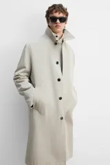 Gabardina color beige de corte relaxed fit, confeccionada en tejido italiano repelente al agua. Tiene cuello solapa, manga larga con puños abotonados, bolsillos de vivo en la cadera, bolsillo interior y abertura en la espalda.