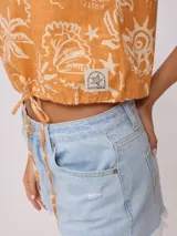 Top corto negro con estampado de flores y figuras geométricas en color crema, con breteles anchos y lazo ajustable en la cintura.