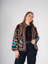 Chaqueta corta negra con bordados florales en tonos naranja, celeste y beige.