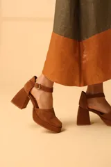 Sandalias negras de charol con plataforma, taco geométrico y pulsera al tobillo con hebilla metálica.